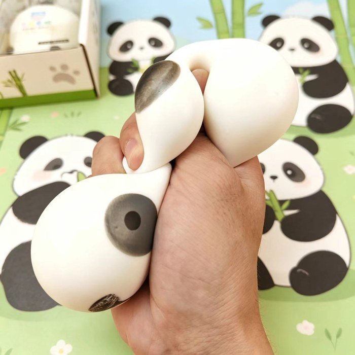 Panda squishy being squeezed with panda display boxes in the background