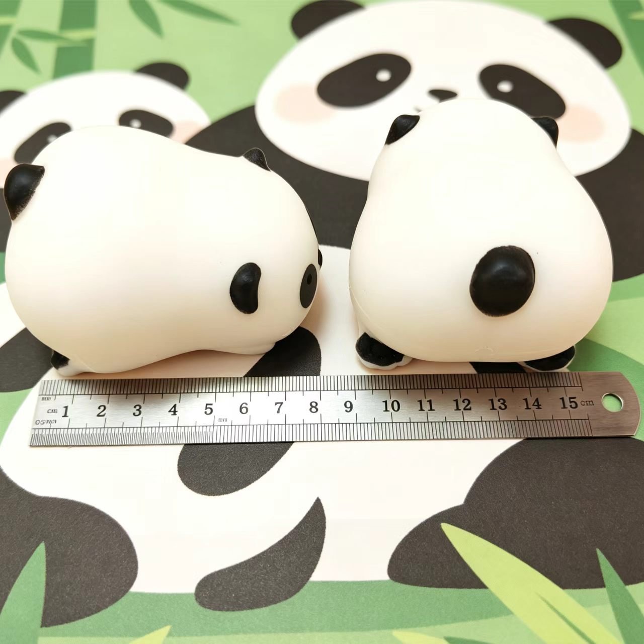 Two panda squishy toys photographed beside a ruler